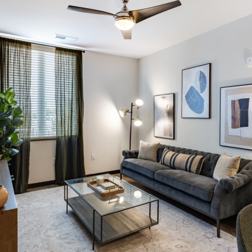 furnished living room with window, ceiling fan and light fixture