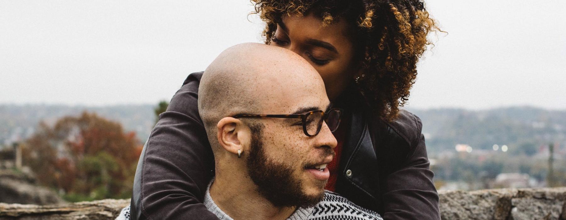 woman hugs a man with glasses