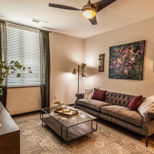 furnished living room with window, ceiling fan and light fixture